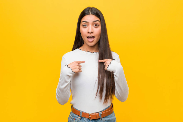 Young pretty arab woman against a yellow background surprised pointing with finger, smiling broadly. - Fotografie, Obrázek