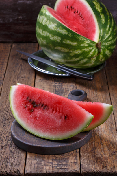 Reife Wassermelone in Scheiben geschnitten auf braunem Holztisch. - Foto, Bild