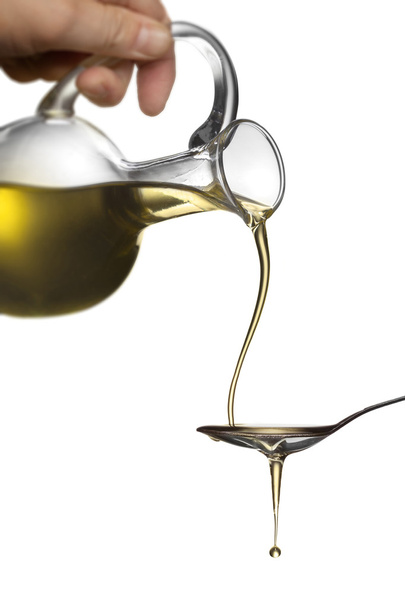 Pouring oil from jar on spoon isolated on white - Fotoğraf, Görsel