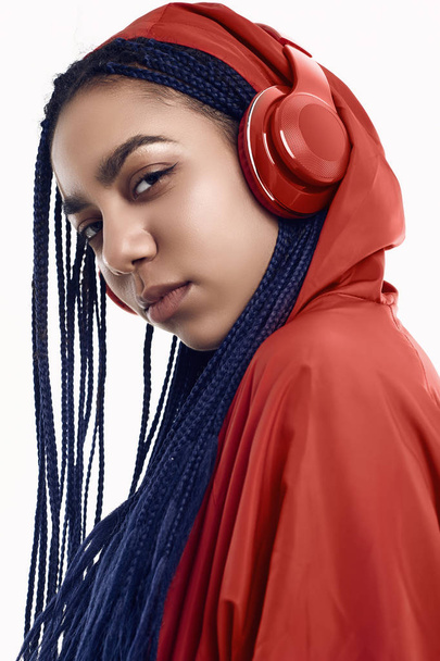 African teenage girl with dreadlocks in red windbreaker listenin - Foto, Imagen