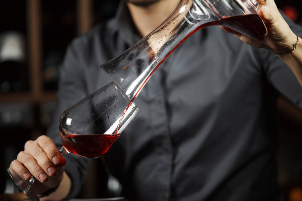 Sommelier pouring wine into glass from mixing bowl. Male waiter - Foto, Bild