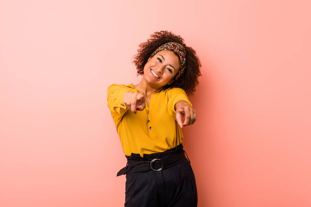 Young african american woman against a pink background cheerful smiles pointing to front. - Fotó, kép