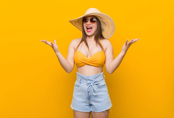Young caucasian woman wearing a straw hat, summer look celebrating a victory or success, he is surprised and shocked. - Фото, изображение