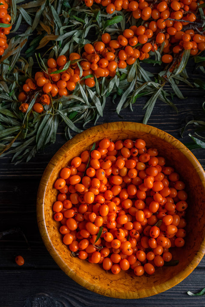 To view of berries and branches of sea buckthorn on a dark wooden background - Foto, Imagen