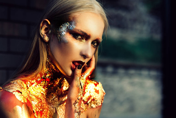 Golden Witch. Beauty fashion Halloween girl with Golden make up. Halloween Lady with holiday Glamour shiny professional makeup. Halloween Fashion model girl with Golden Makeup. - Foto, Imagen