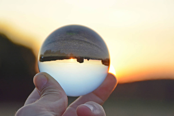mit einer Glaskugel in der Hand, die einen Sonnenuntergang in Deutschland zeigt - Foto, Bild