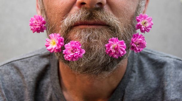 Brutale man met bloemen in zijn baard. - Foto, afbeelding