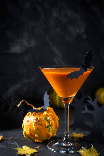 Oranje martini cocktails met vleermuizen en decor voor Halloween-feest, op donkere achtergrond - Foto, afbeelding