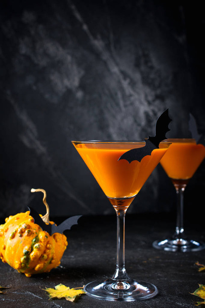Bebida laranja de Halloween com morcegos no fundo escuro, assustador
 - Foto, Imagem