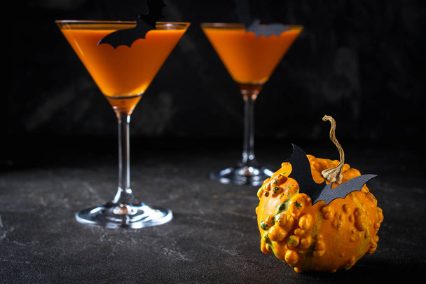 Drôle de citrouille avec des chauves-souris noires et un cocktail orange dans un verre sur Halloween
 - Photo, image