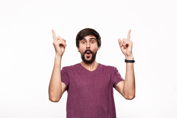 Homme brunet excité dans une chemise violette avec barbe et moustaches pointant avec ses doigts debout isolé sur fond blanc. Lieu du produit et publicité
. - Photo, image