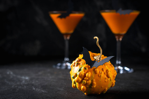 Забавная тыква с черными летучими мышами и оранжевым коктейлем в стакане на Хэллоуин
 - Фото, изображение