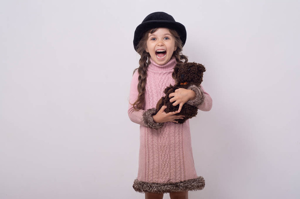 überraschte Mädchen mit Teddybär. Kind mit Retro-Hut und Vintage-Teddybär.   - Foto, Bild