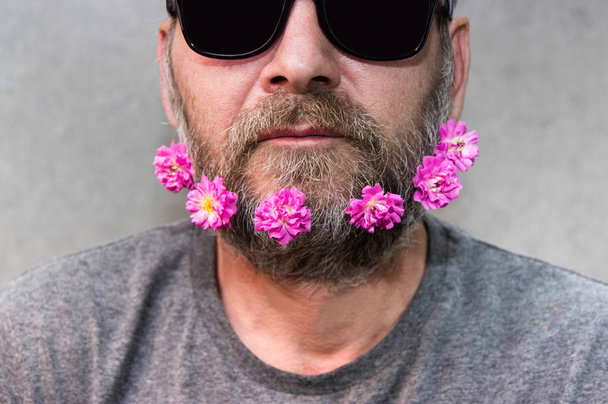 Brutal man with flowers in his beard. - Photo, Image