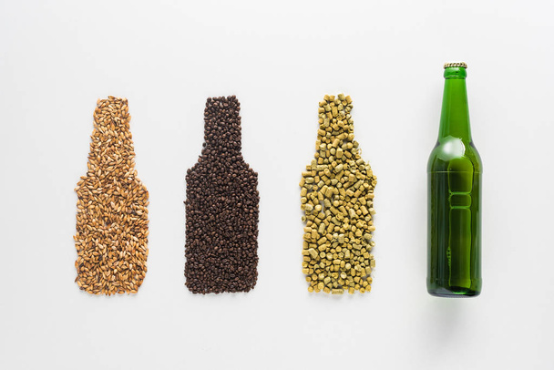小麦、コーヒー粒、白で分離されたプレスホップの近くのビールのボトルのトップビュー - 写真・画像