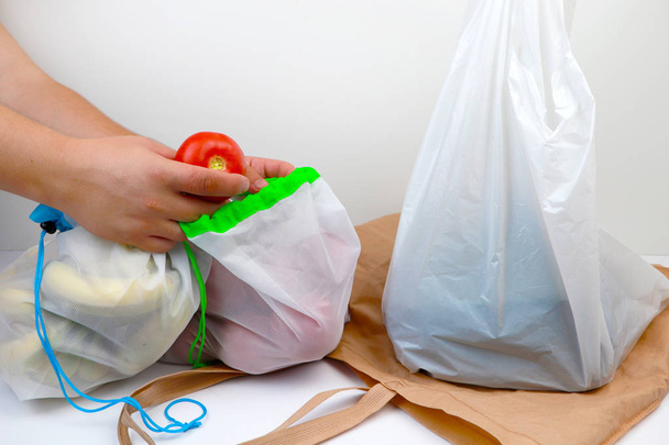 Sebze ve meyve ile alışveriş için plastik torba ve eko doğal yeniden tote çanta. Yeniden kullanılabilir şeyler lehine bilinçli bir seçim kavramı ve tek kullanımlık plastik malların reddi. Çevre koruma, felsefe sıfır batı - Fotoğraf, Görsel