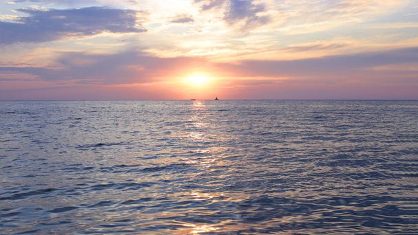 Φωτεινό ηλιοβασίλεμα στη θάλασσα πολύ αέρα και νερό μια στενή ακτογραμμή, αυγή κοντά στο Aqua μια διαβάθμιση των ηλιακών χρωμάτων στον ουρανό - Φωτογραφία, εικόνα