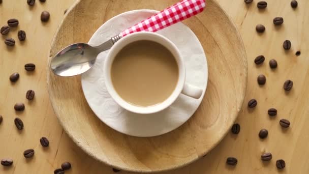 Top view of coffee with spoon on decorative plate on wooden table - Video