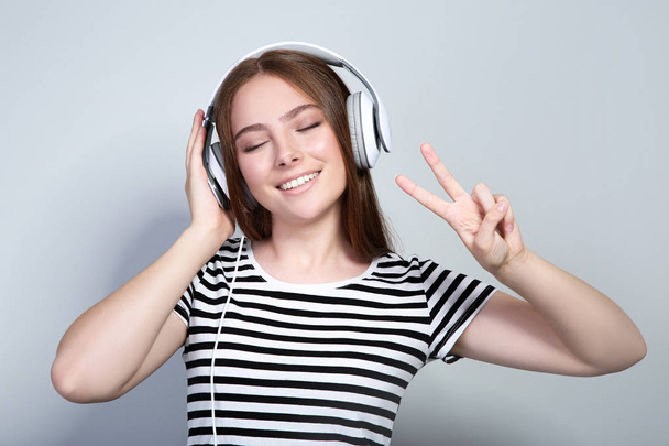 Young beautiful woman with headphones on grey background - Foto, afbeelding