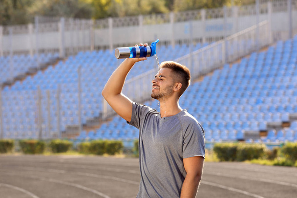 Hombre deportivo guapo refrescándose con agua después de entrenar al aire libre
 - Foto, Imagen