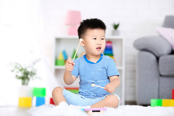 Beautiful boy sitting and playing on musical toy at home - Foto, Imagen