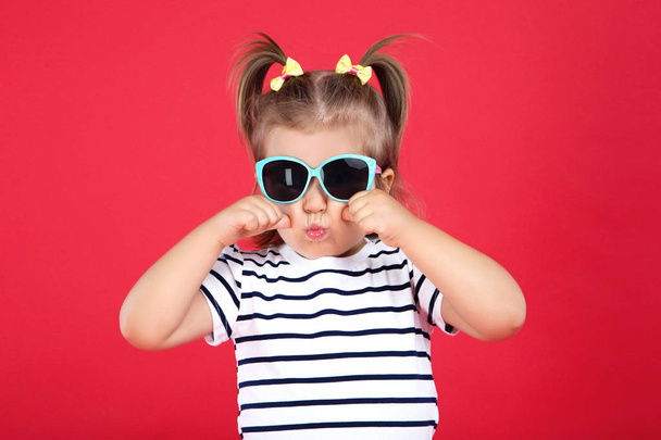 Cute little girl in sunglasses on red background - Φωτογραφία, εικόνα