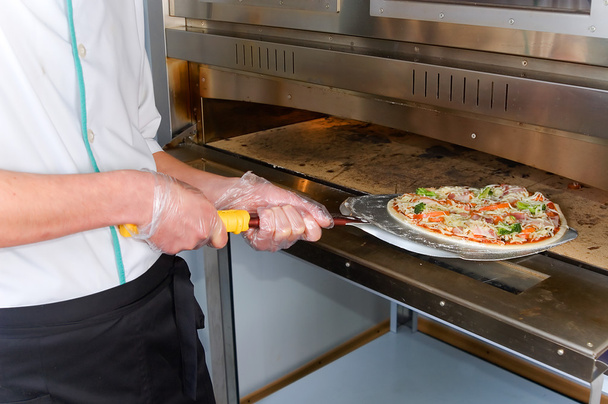Il cuoco tira fuori una pizza pronta dal forno
 - Foto, immagini