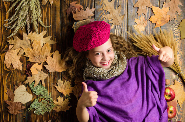 Fashion trend fall season. Girl lay wooden background fallen maple leaves top view. Hat accessory fashion detail. Kid girl bright soft knitted hat enjoy autumn. Autumn fashion hat accessory - 写真・画像