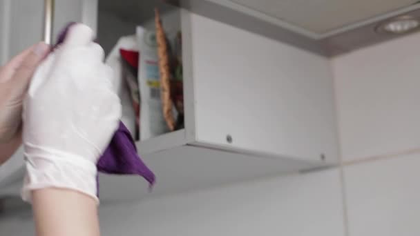 Close-up ama de casa femenina con guantes haciendo limpieza armario de la cocina usando trapo ángulo bajo
 - Metraje, vídeo