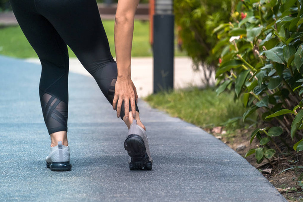 Mulher asiática segurando seu tornozelo após uma lesão de torção durante a corrida
 - Foto, Imagem