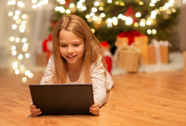smiling girl with tablet pc at christmas home - Fotó, kép