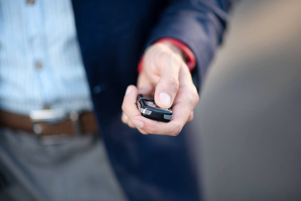 Businessman holding car keys while running late for work - Foto, afbeelding