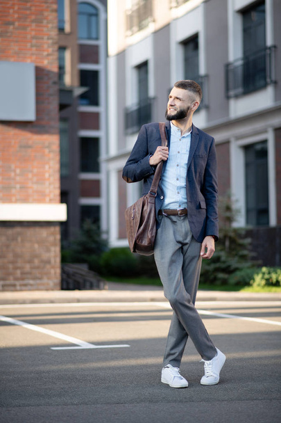 Stylish businessman wearing grey trousers standing near his house - Zdjęcie, obraz