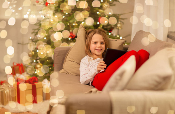 smiling girl with tablet pc at christmas home - Foto, Imagen