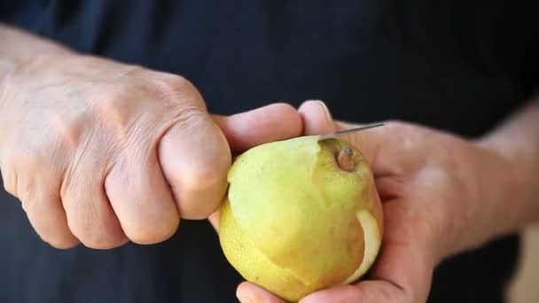 Older man removes peel from a fresh pear - Felvétel, videó