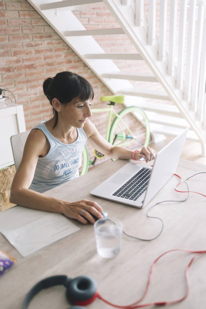 Nainen, jolla on kannettava tietokone töissä kotona
 - Valokuva, kuva
