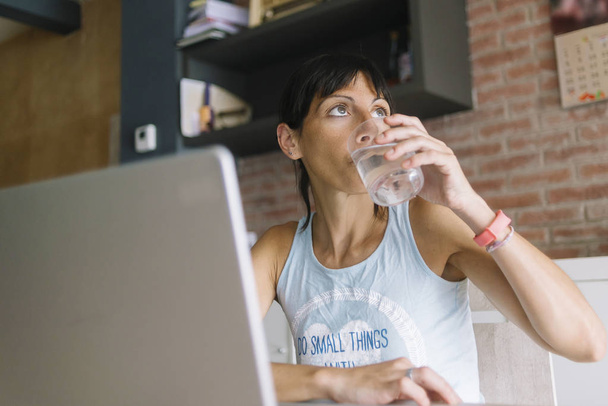 Taze bir bardak tutarken evde çalışan dizüstü bilgisayar ile Kadın - Fotoğraf, Görsel