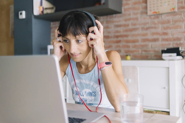Headp ile müzik dinlerken evde çalışan dizüstü bilgisayar ile kadın - Fotoğraf, Görsel