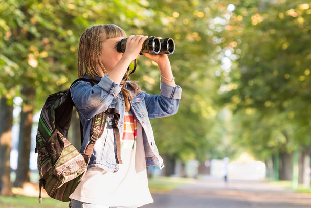 Teenage girl with binoculars in a park - Фото, зображення