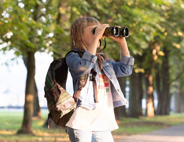 Teenage girl with binoculars in a park - Fotó, kép