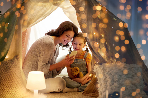 happy family with smartphone in kids tent at home - Photo, image