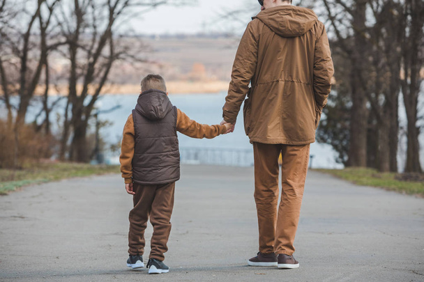 батько з сином, що йде парком тримає руки
 - Фото, зображення