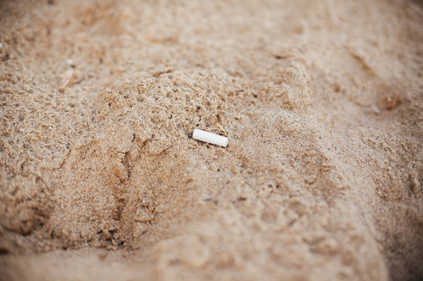 Tupakantumppi hiekassa, roskaväkeä rannalla. Muovipöly
 - Valokuva, kuva