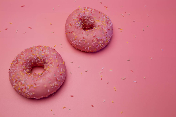 Two isolated glazed donuts with colorful candy shavings. - 写真・画像