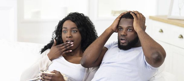 Emotional black couple watching horror movie on tv - Valokuva, kuva