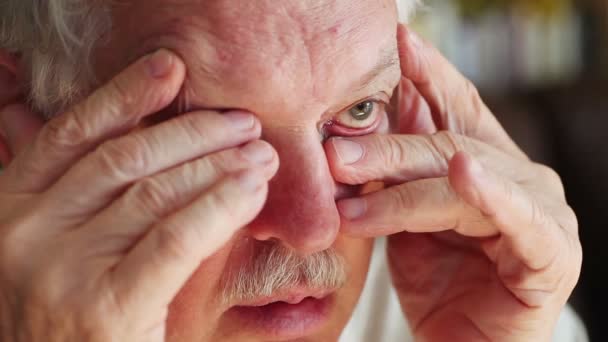 Senior man met onvrijwillige handbeweging met vingers over één oog - Video