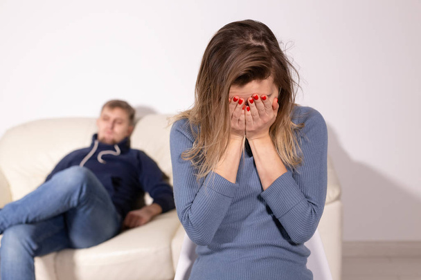 perheväkivalta, pahoinpitely ja perhekäsite - itkevä nainen ja hänen miehensä taustalla
 - Valokuva, kuva