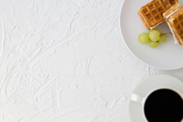 Reggeli. Csésze kávé és a belga gofri, friss zöld szőlő, fehér háttér felső nézetben a másolási tér. - Fotó, kép