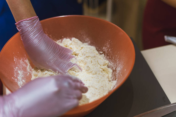 girl kneads dough made from flour and butter. A cook in gloves prevents flour from making dough - Fotó, kép