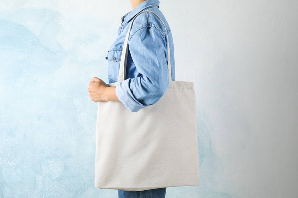 Mujer joven sosteniendo bolsa de mano sobre fondo azul, spac vacío
 - Foto, Imagen